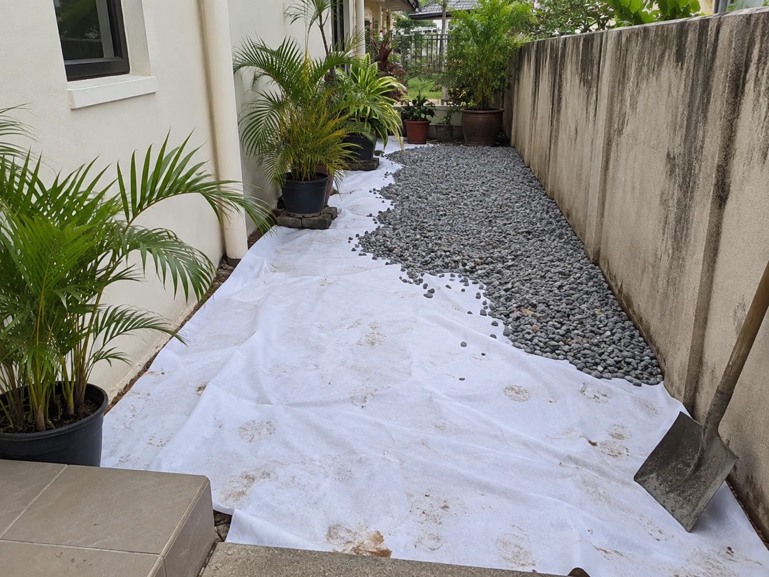 AeroTex under grey stones along a house side yard